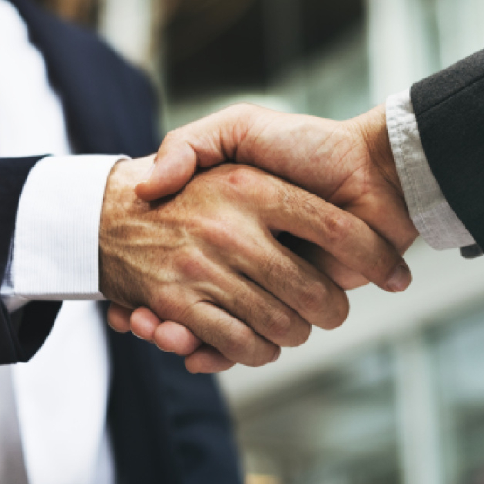 Dos empresarios dándose la mano después de concretar una fusión empresarial